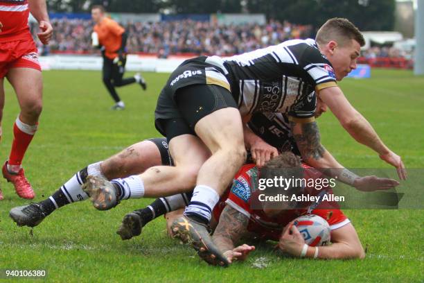 Thomas Minns of Hull KR scores a try as Jamie Shaul and Jake Connor of Hull FC tackle him during the BetFred Super League match between Hull KR and...