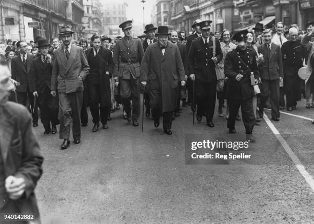 British Prime Minister Winston Churchill is accompanied by crowds as he visits sites in London damaged by bombing the night before, World War II,...