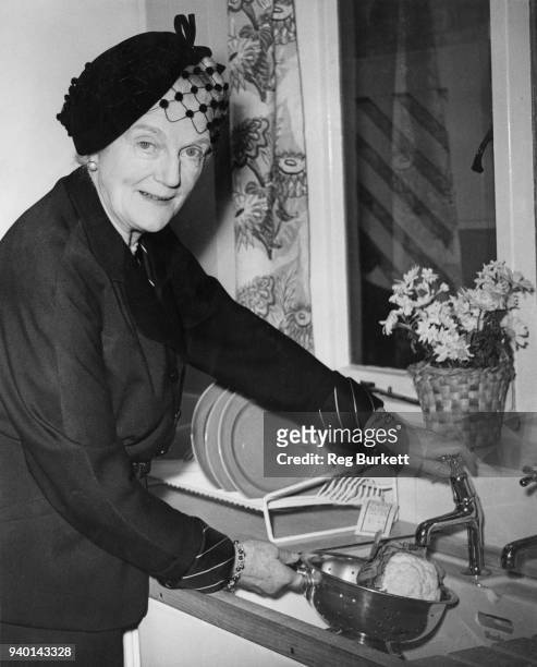 Clementine Churchill , wife of Prime Minister Winston Churchill, washes a cauliflower in a kitchen sink at the People's House at the Ideal Home...