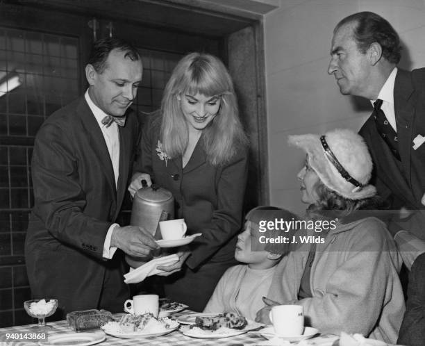 From left to right, Australian actors Bill Kerr , Diane Cilento , Kitty Bluett and Dick Bentley serve tea to 9-year-old Joan Sidebottom of Llandudno...