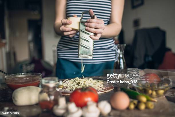 woman grating cheese on pizza - parmesan cheese pizza stock pictures, royalty-free photos & images
