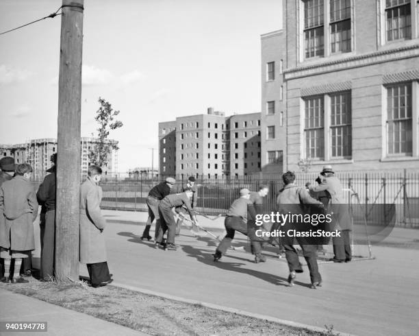 1930s GROUP TEEN BOYS PLAYING STREET HOCKEY IN BOROUGH OF QUEENS NEW YORK CITY USA