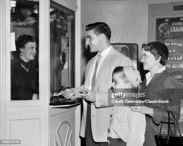 1950s FAMILY MOTHER FATHER BOY BUYING ADMISSION AT MOVIE THEATER TICKET BOX OFFICE