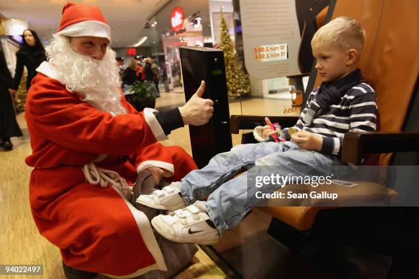 Man dressed as Santa Claus offer sweets to children at the Alexa shopping mall on December 5, 2009 in Berlin, Germany. Retailers are hoping for a...