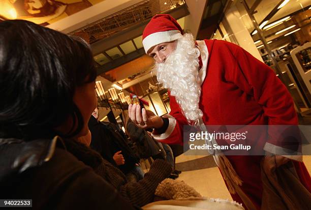 Man dressed as Santa Claus offer sweets to children at the Alexa shopping mall on December 5, 2009 in Berlin, Germany. Retailers are hoping for a...