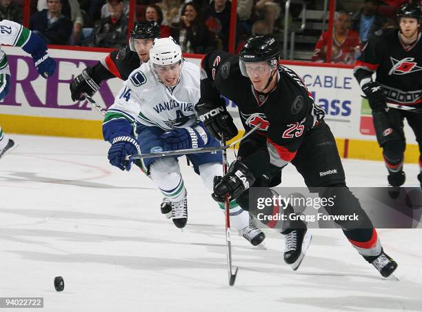 Joni Pitkanen of the Carolina Hurricanes carries the puck away from Alexandre Burrows of the Vancouver Canucks during a NHL game on December 5, 2009...