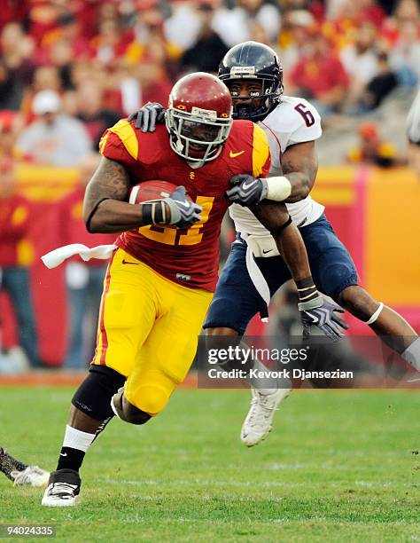 Tailback Allen Bradford of the USC Trojans drags cornerback Devin Ross of the Arizona Wildcats as he rushes for a gain during the second quarter of...