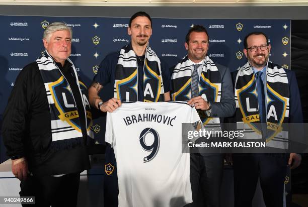 Galaxy footballer Zlatan Ibrahimovic holds up his new team jersey with coach Sigi Schmid , club president Chris Klein and AEG President Dan Beckerman...