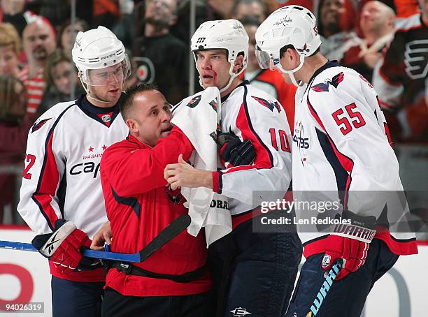 Matt Bradley of the of the Washington Capitals is helped off the ice by Mike Green, Jeff Schultz and a trainer after fighting with Dan Carcillo of...