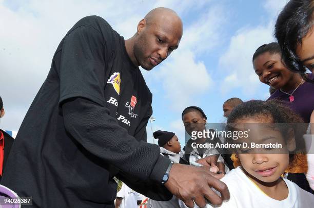 Lamar Odom of the Los Angeles Lakers autographs a t-shirt for a participant at the Los Angeles Lakers annual Holiday Party for kids on December 5,...