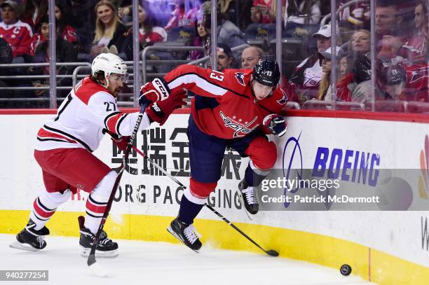 Jakub Vrana of the Washington Capitals and Justin Faulk of the Carolina Hurricanes battle for the puck in the first period at Capital One Arena on...