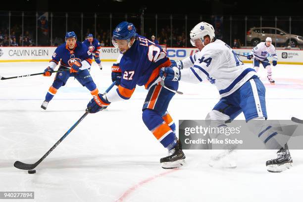 Anders Lee of the New York Islanders plays the puck against Morgan Rielly of the Toronto Maple Leafs at Barclays Center on March 30, 2018 in New York...