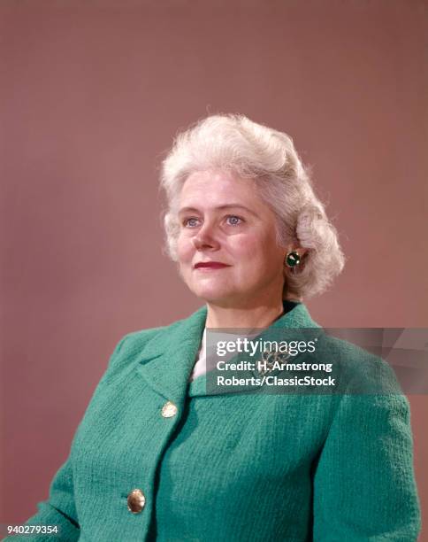 1950s 1960s PORTRAIT HALF SMILING SENIOR WOMAN BEIGE BACKGROUND GRAY SILVER HAIR WEAR GREEN KNIT JACKET GOLD BUTTONS BROOCH