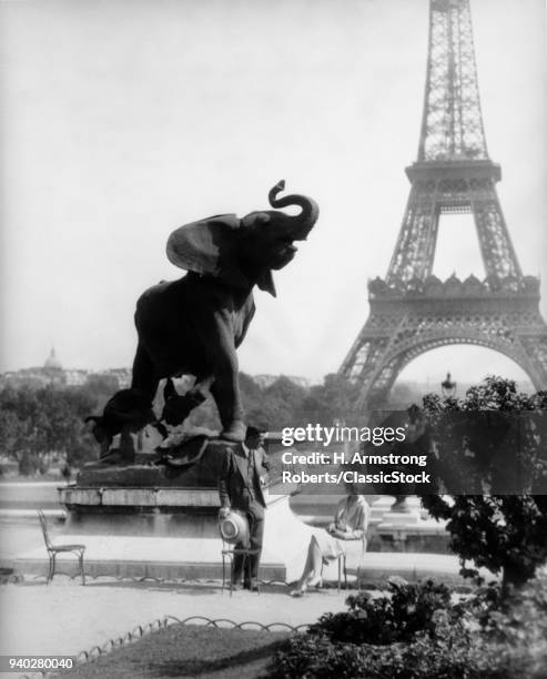 1920s COUPLE MAN WOMAN ELEPHANT STATUE GARDEN OF TROCADERO WITH EIFFEL TOWER IN BACKGROUND PARIS FRANCE