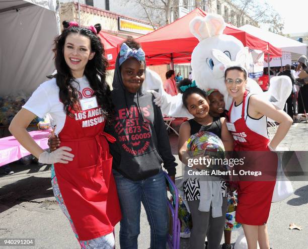 Actress Natasha Blasick and actress Christina DeRosa pose with children at the Los Angeles Mission Easter Charity Event held at Los Angeles Mission...