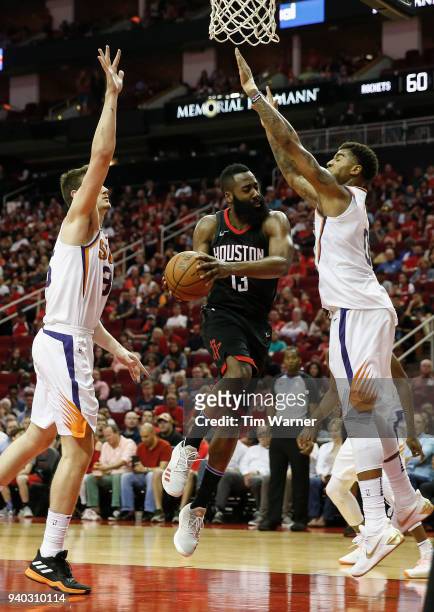 James Harden of the Houston Rockets looks to pass the ball defended by Marquese Chriss of the Phoenix Suns and Alec Peters in the second half at...