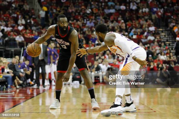 James Harden of the Houston Rockets controls the ball defended by Troy Daniels of the Phoenix Suns in the second half at Toyota Center on March 30,...