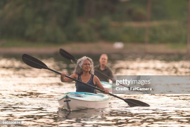 an older couple enjoy a late evening of kayaking on the river - energy independence stock pictures, royalty-free photos & images