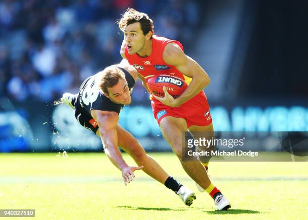 Lachie Weller of the Suns runs with the ball past David Cuningham of the Blues during the round two AFL match between the Carlton Blues and the Gold...