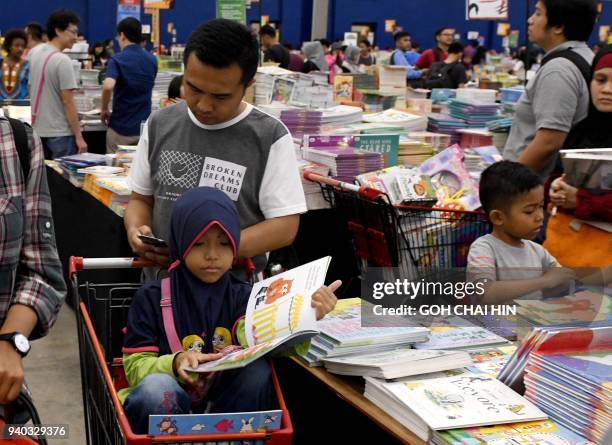 This picture taken on March 30, 2018 shows families browsing through books at the Big Bad Wolf book sale in Serpong in the suburbs of Jakarta. / AFP...