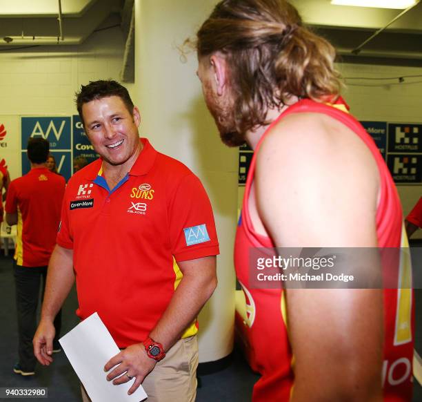 Suns head coach Stuart Dew walks celebrates the win with Aaron Young of the Suns during the round two AFL match between the Carlton Blues and the...