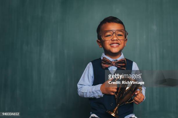 young retro nerd boy in classroom with trophy - golden boy stock pictures, royalty-free photos & images