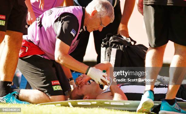 Tim Broomhead of the Magpies is given the green whistle as he lies on the field with a broken leg during the round two AFL match between the...