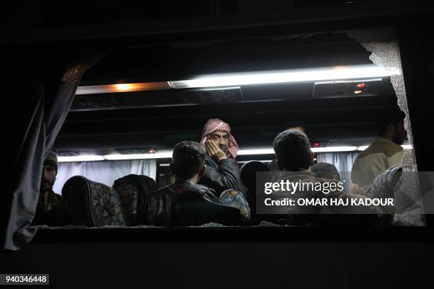 Syrian civilians and rebels evacuated from the Eastern Ghouta region are seen aboard a bus as they arrive in Qalaat al-Madiq, some 45 kilometres...