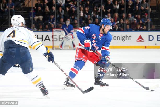 Peter Holland of the New York Rangers skates with the puck against Josh Gorges of the Buffalo Sabres at Madison Square Garden on March 24, 2018 in...