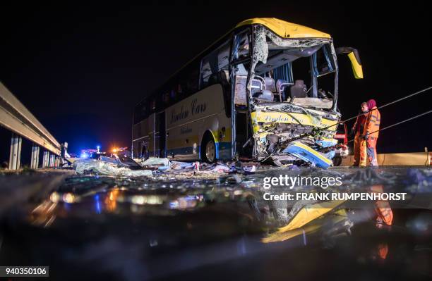 Rescue workers stand near a heavily damaged bus after a crash with a truck on the Autobahn 3 motorway on March 31 in Waldaschaff, near Aschaffenburg...