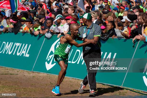 Runner is helped by an official after crossing the finish line of the Two Oceans ultra-marathon, the Two Oceans ultra-marathon, on March 31 in Cape...