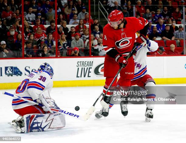 The Carolina Hurricanes' Elias Lindholm tries to get the puck past the New York Rangers' Henrik Lundqvist during the first period at PNC Arena in...