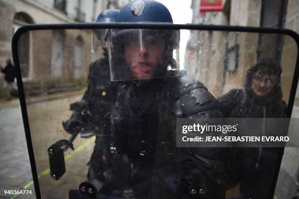Riot policemen stand behind a shield during clashes with protesters while members of associations, unions and collectives, supporting migrants but...