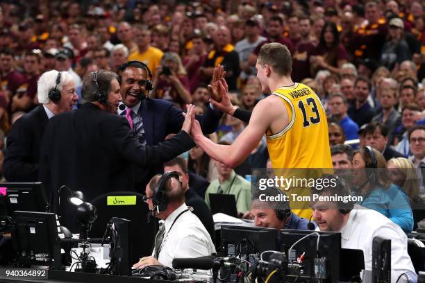 Moritz Wagner of the Michigan Wolverines high fives TV personalities Jim Nantz, Bill Raftery and Grant Hill after jumping off the court in the second...