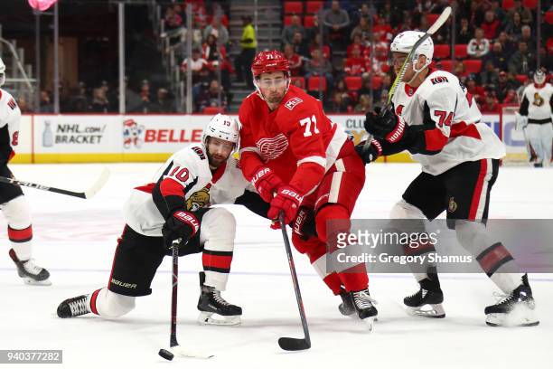 Dylan Larkin of the Detroit Red Wings battles for the puck with Tom Pyatt and Mark Borowiecki of the Ottawa Senators during the first period at...