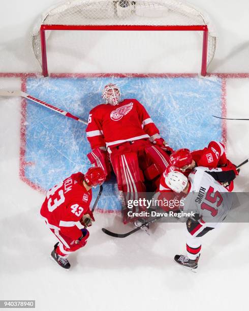 Jimmy Howard of the Detroit Red Wings lays on the puck as teammates Darren Helm and Jonathan Ericsson defend against Zack Smith of the Ottawa...