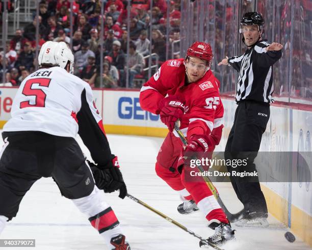 Danny DeKeyser of the Detroit Red Wings passes the puck along the boards in front of Cody Ceci of the Ottawa Senators during an NHL game at Little...