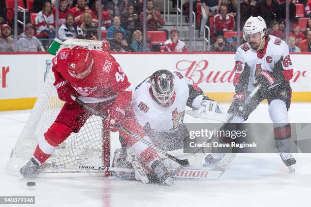 Darren Helm of the Detroit Red Wings battles for the puck in front of goaltender Mike Condon and Erik Karlsson of the Ottawa Senators during an NHL...