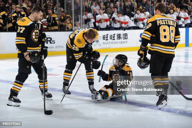 Patrice Bergeron, Brandon Carlo and David Pastrnak of the Boston Bruins say hello to the Kids Captain before the game against the Florida Panthers at...