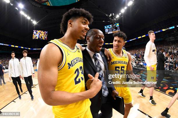 Ibi Watson and Eli Brooks of the Michigan Wolverines celebrate with their coach after defeating the Loyola Ramblers in the 2018 NCAA Photos via Getty...