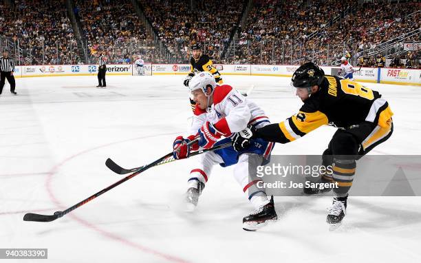 Brendan Gallagher of the Montreal Canadiens and Brian Dumoulin of the Pittsburgh Penguins battle for the puck at PPG Paints Arena on March 31, 2018...