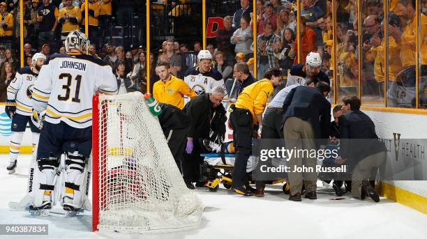 Goalie Chad Johnson looks on as medical staff tend to Victor Antipin of the Buffalo Sabres after a hit by Scott Hartnell of the Nashville Predators...