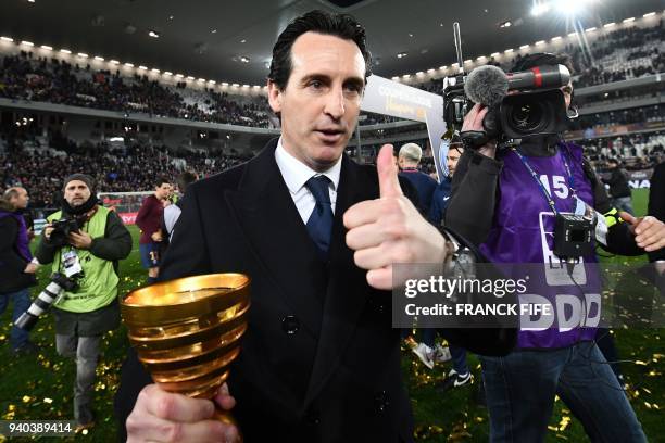 Paris Saint-Germain's Spanish headcoach Unai Emery holds the trophy as he celebrates after victory in the French League Cup final football match...