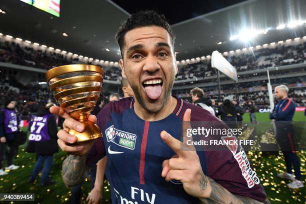 Paris Saint-Germain's Brazilian defender Daniel Alves holds the trophy as he celebrates after victory in the French League Cup final football match...