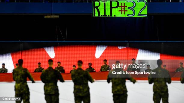 Members of the Canadian military unfold the Canadian flag as a fan's home made sign honouring the late Roy Halladay is seen overhead before the MLB...