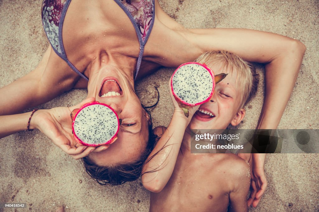Garçon et femme heureuse met pitaya comme des lunettes.