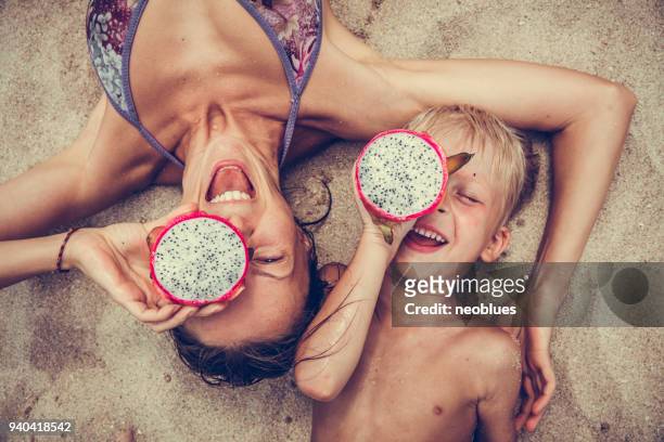 garçon et femme heureuse met pitaya comme des lunettes. - children in summer photos et images de collection