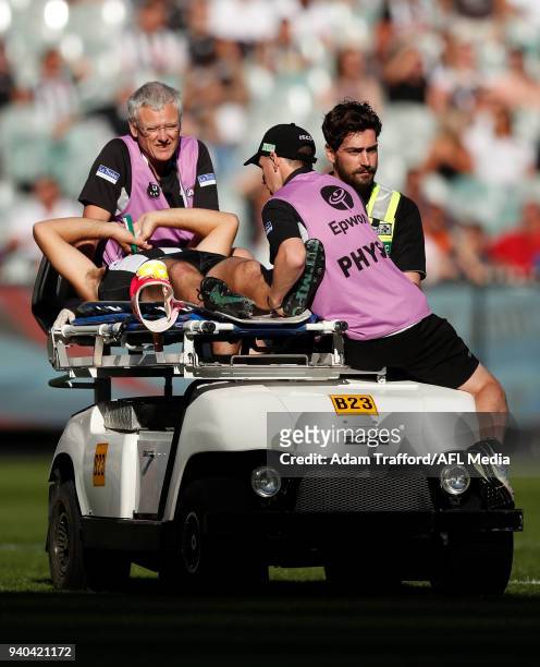 Tim Broomhead of the Magpies come off the ground injured after hitting his leg on the goalpost during the 2018 AFL round 02 match between the...