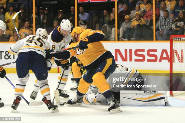 Buffalo Sabres goalie Chad Johnson tries to cover the puck as Sabres defenseman Brendan Guhle and Sabres defenseman Casey Nelson defend against...