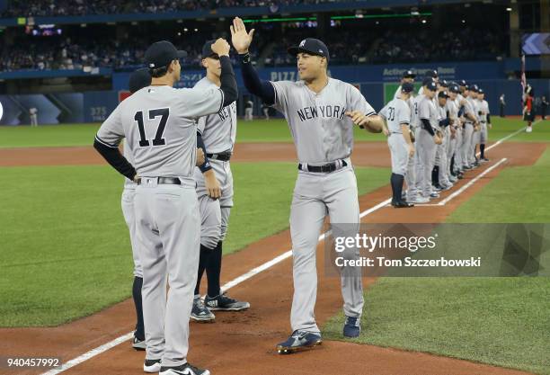 Giancarlo Stanton of the New York Yankees is welcomed by manager Aaron Boone and teammates during pre-game introductions on Opening Day before the...